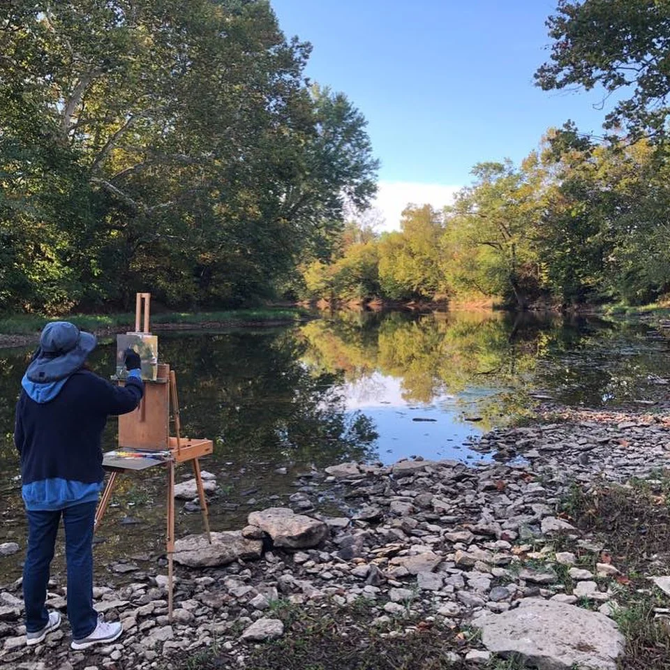 Person painting on a creekside